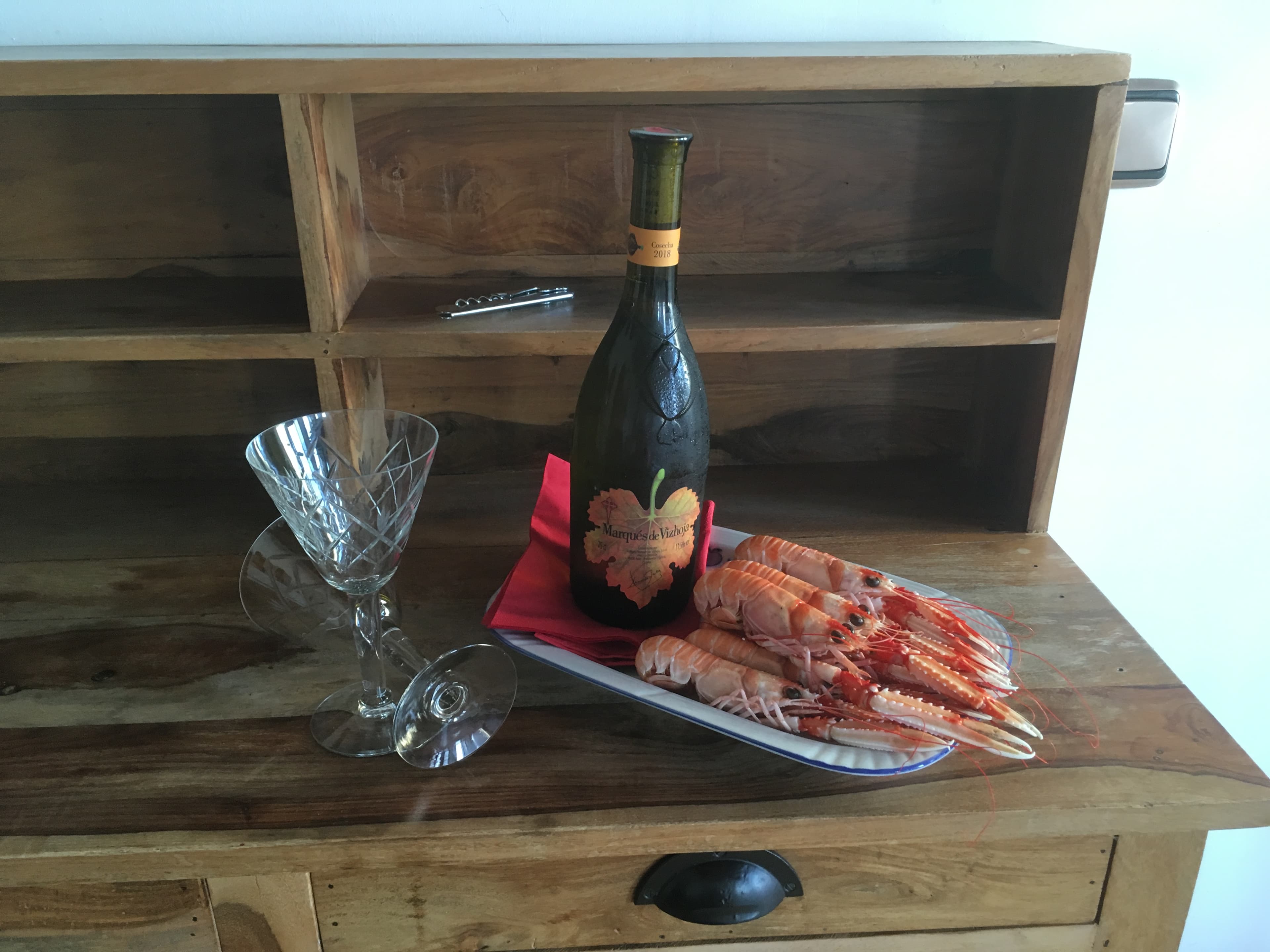 A bottle of Albariño wine beside a plate of fresh Galician langoustines